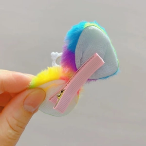Dettaglio della clip in metallo avvolta nel nastro rosa e texture in peluche colorato