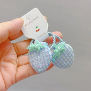 Détail des accessoires cheveux fraise à carreaux bleus avec paillettes sur support carton
