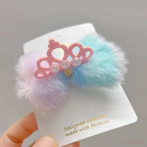 Dettaglio molletta a corona rosa con perle sintetiche e morbidi pompon in peluche