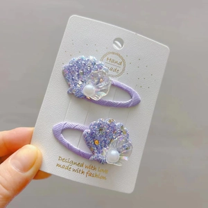Détail des pinces à cheveux en forme de coquillage pailleté violet avec perles