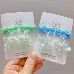 Detail of handmade bow hair clips with hanging beads, pearls and lace ribbons