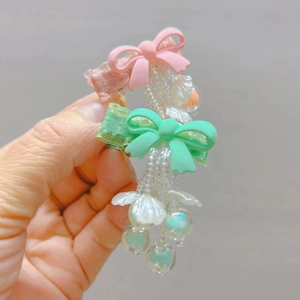 Detailed view of handmade bow hair clips with shell pearl tassels and colorful beads
