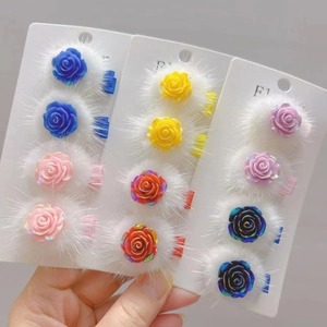 Détail des pinces à cheveux rose en résine et pompon en peluche sur carte blanche