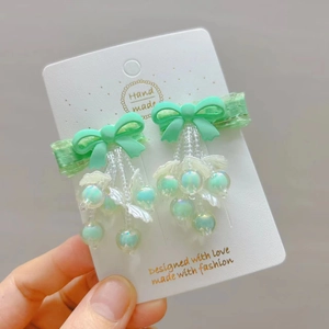 Detail of handmade light green bow hair clips with pearls and shell flower pendants