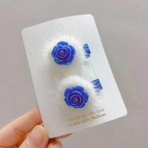 Détail de pinces à cheveux rose bleue avec bordure en fausse fourrure blanche sur carte