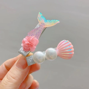 Detailed close-up of girls mermaid hair clips with pink shell, pearl and floral accents