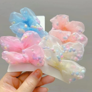 Dettaglio di quattro fermagli per capelli a fiocco in organza colorata con perline per bimbe