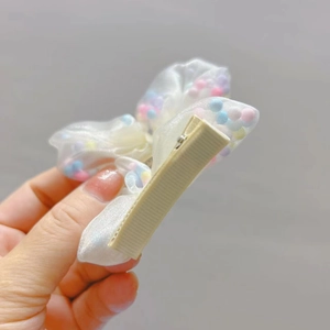 Dettaglio del retro con clip in metallo avvolta in nastro su fiocco in tulle