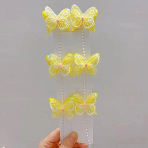 Détail de barrettes papillon brodées jaunes avec d'élégants glands en fausses perles