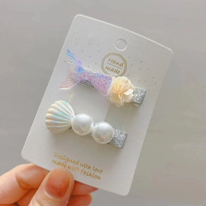 Detail view of mermaid tail and seashell hair clips with pearls on a card