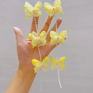 Vue détaillée de pinces à cheveux papillon en dentelle jaune avec chaînes de perles