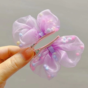 Dettaglio di fermagli per capelli in organza viola con pompon colorati macaron