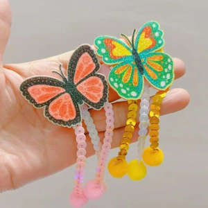Vue détaillée de pinces à cheveux papillon pailletées avec sequins et pompons