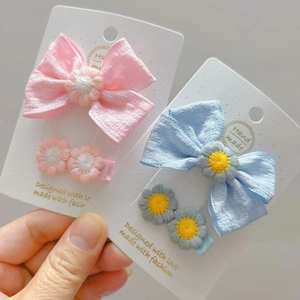 Dettaglio di fermagli per capelli con fiocco rosa e blu e margherite ricamate