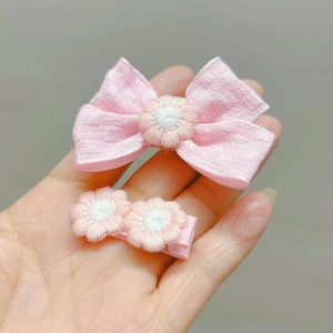 Dettaglio della clip per capelli con fiocco rosa e forcine con margherite per bambina