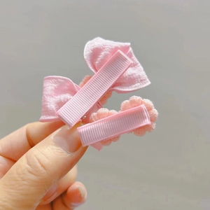 Dettaglio di fiocco in tessuto rosa e fermagli per capelli a margherita con clip rivestite