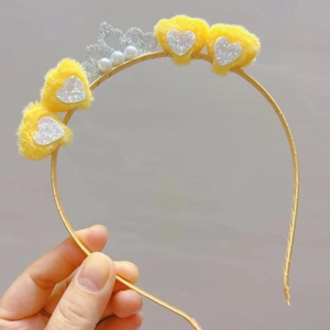 Detail of yellow plush heart headband with a silver glitter crown and white pearls