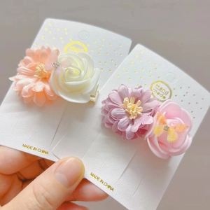 Detail van handgemaakte vlinder haarclips met satijnen bloemblaadjes en glanzende strass