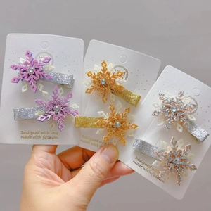 Détail de pinces à cheveux flocon de neige pailletées avec strass sur présentoir