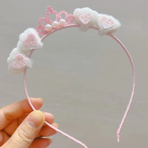 Detail of pink crown headband with white plush balls and sparkly sequin hearts