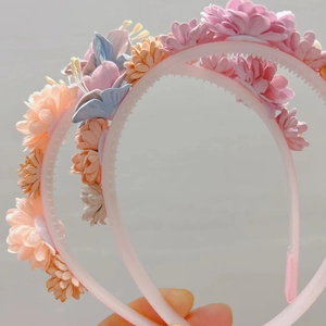 Détail d'un serre-tête rose avec dents antidérapantes et fleurs en tissu pastel