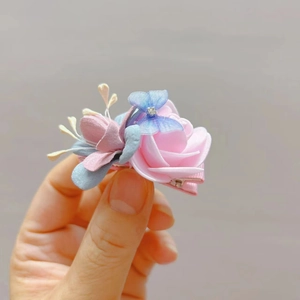 Detail van handgemaakte bloemenclip met roze zijden rozen en blauwe bloemblaadjes
