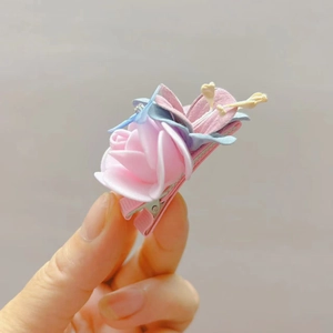 Detail van roze stoffen bloem haarclip met blauwe bladeren en metalen krokodillenklem