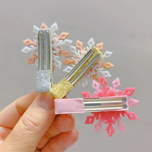 Détail de trois barrettes flocon de neige pailletées en argent, or et rose avec clips en métal