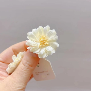 Gros plan détaillé d'un accessoire à cheveux en fleur de tissu blanc avec étamine jaune