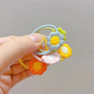 Détail d'élastiques à cheveux avec fleurs de marguerites brodées et cordes en spirale