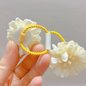 Détail de l'élastique tressé jaune avec deux breloques de fleurs marguerites blanches 3D