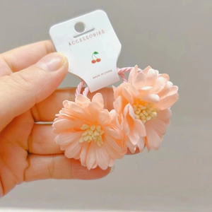 Détail des élastiques à cheveux marguerite rose avec pétales en tissu multicouches