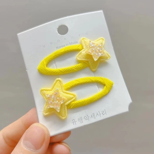 Detail of yellow star hair clips with glitter fabric texture on display card