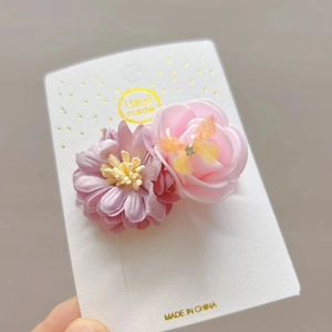Detail van handgemaakte bloemenhaarspeld met roze camellia en een sierlijke vlinder