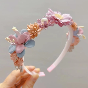 Détails d'un serre-tête fleuri en tissu avec des perles blanches et des pétales multicouches