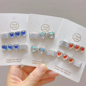 Close-up of glittery heart hair clips in blue, iris and red on white cards