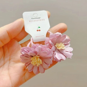 Détail de chouchous fleurs en tissu rose avec élastiques sur une carte de support