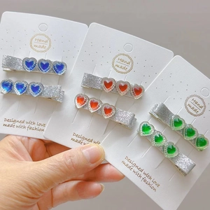 Detail of colorful heart crystal hair clips in red, blue, and green with handmade card
