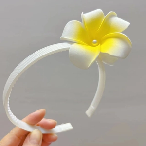Détail du serre-tête blanc côtelé avec fleur de frangipanier dégradée jaune et perle