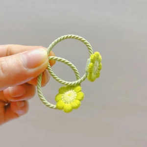 Détail d'élastiques à cheveux verts avec breloques de tournesol tricotées pour filles