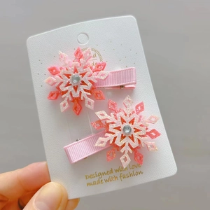 Vue détaillée des pinces à cheveux flocon de neige rose pailleté sur carte cadeau