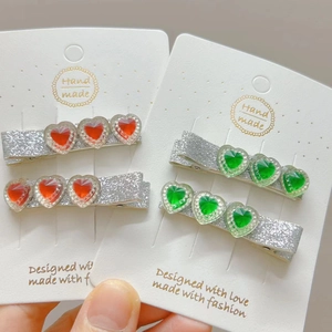 Detail of red and green heart crystal hair clips on a white handmade display card
