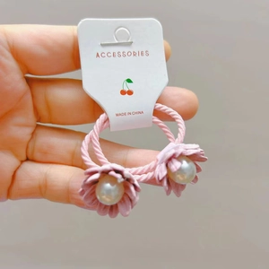Détail de chouchous fleurs roses avec perles brillantes sur carte de présentation blanche
