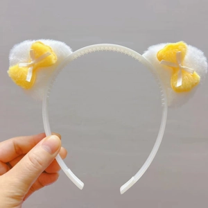 Détail du serre-tête oreilles de chat en peluche avec nœuds jaunes et base antidérapante