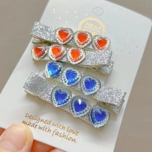 Detail of four-piece heart gemstone hair clips with red and blue crystals and silver glitter