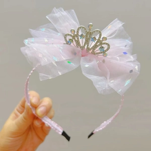 Dettaglio del cerchietto con fiocco in rete rosa e corona di strass per bambina