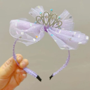 Dettaglio di un cerchietto con fiocco in tulle viola e corona scintillante decorata