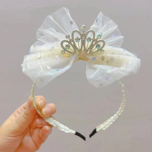 Dettaglio del cerchietto per bambina con fiocco bianco glitterato e corona di strass