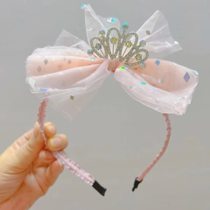 Dettaglio del cerchietto con fiocco in tulle rosa, corona d'argento e strass scintillanti