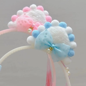 Close-up of plush cat ear headband with mesh bow, pearl pendant and silk tassels